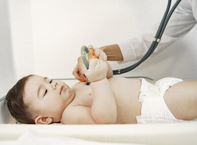 Doctor with stethoscope. Baby without clothes. Examination by a doctor.